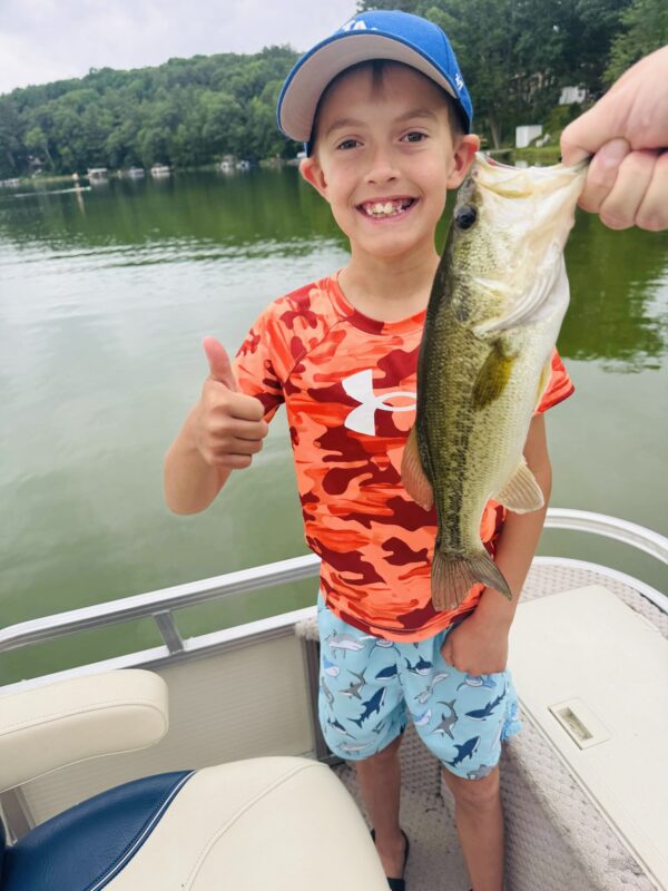 Kid giving a thumbs up with a chunky largemouth bass