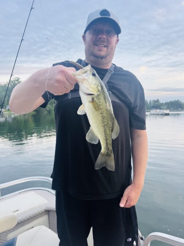 Angler holding a largemouth bass at dusk on the pontoon