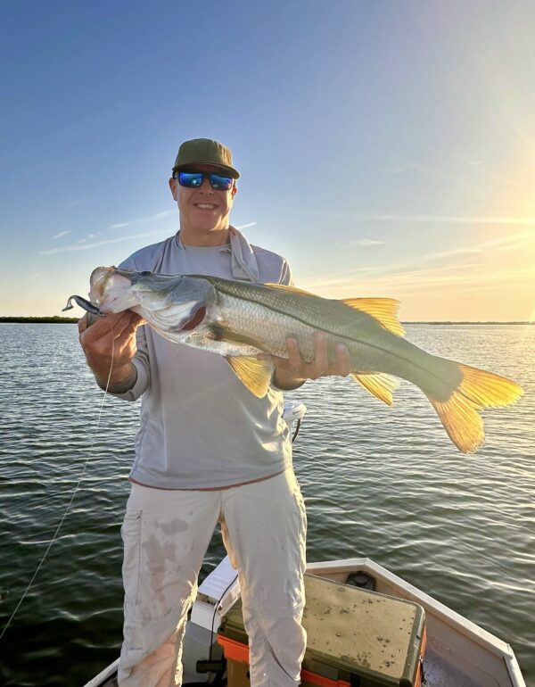Angler holding a snook at sunset on the saltwater flats