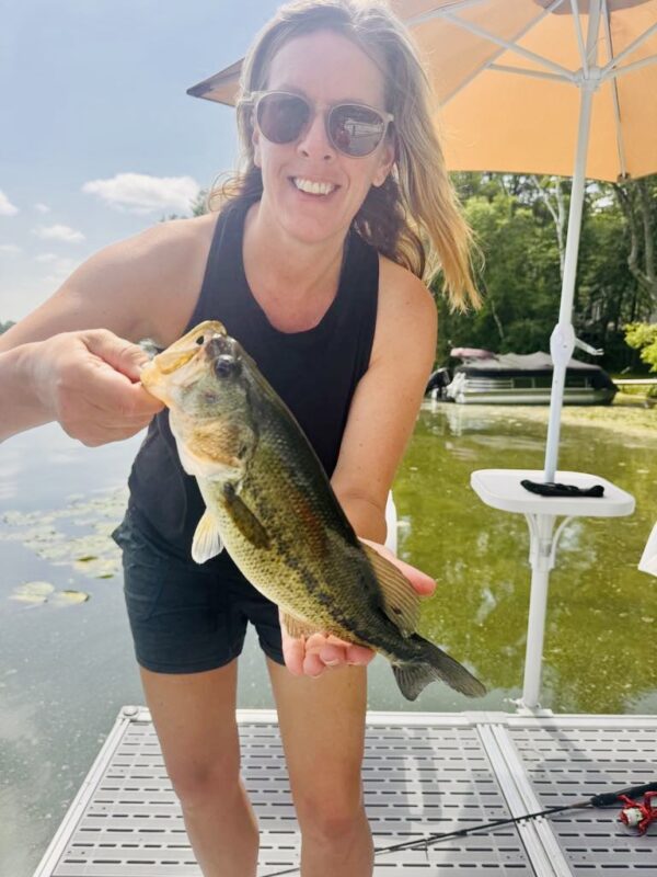 Angler on a swim dock holding a big largemouth bass