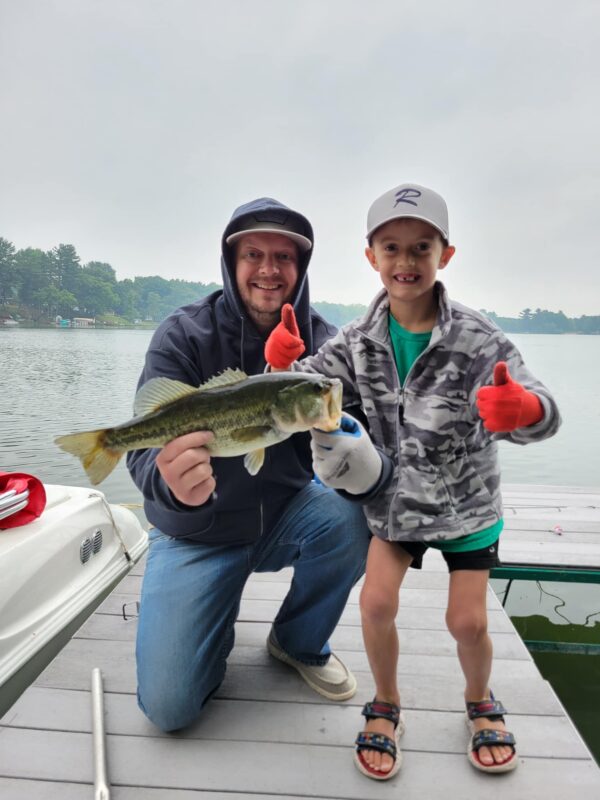 Dad and son on a dock with a largemouth bass