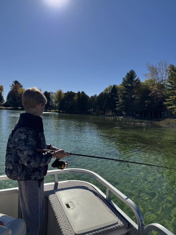 Young angler casting from a pontoon on a clear fall lake