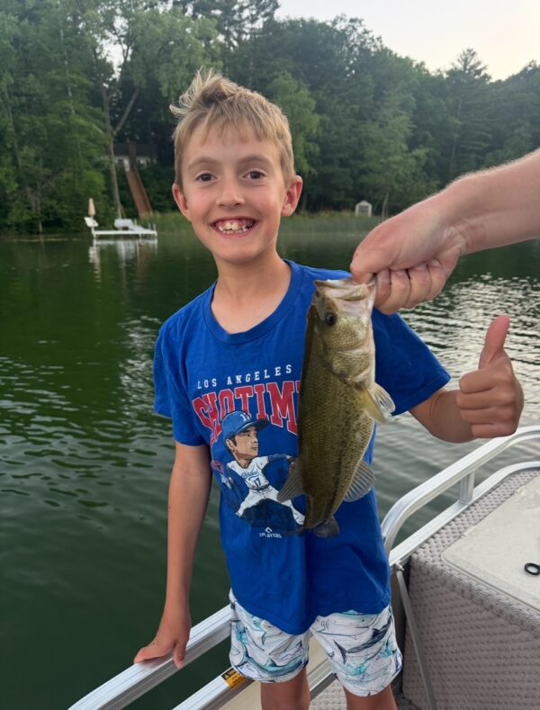 Kid holding a bass caught at sunset off the pontoon