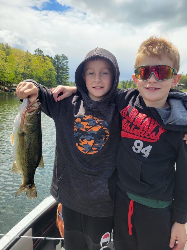 Two young anglers showing off a largemouth bass from the boat