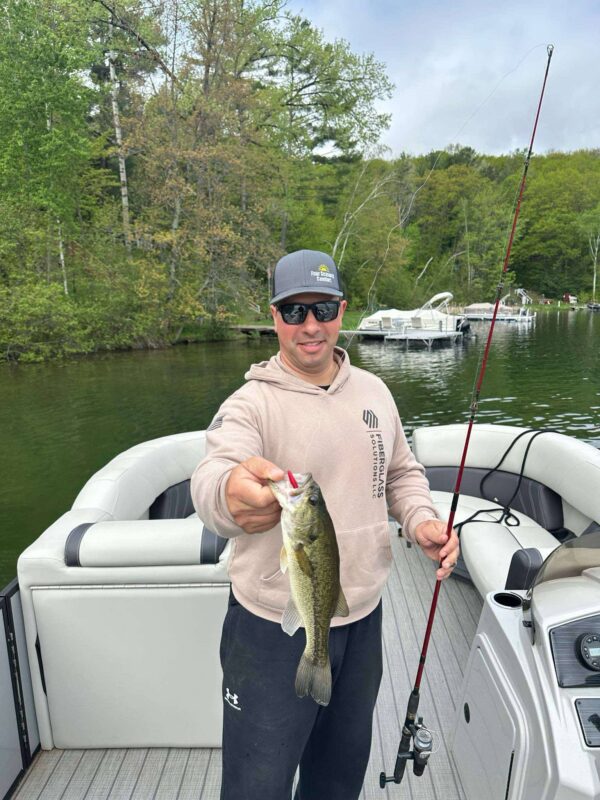 Angler on a pontoon holding a largemouth bass caught on a Yeet stick worm