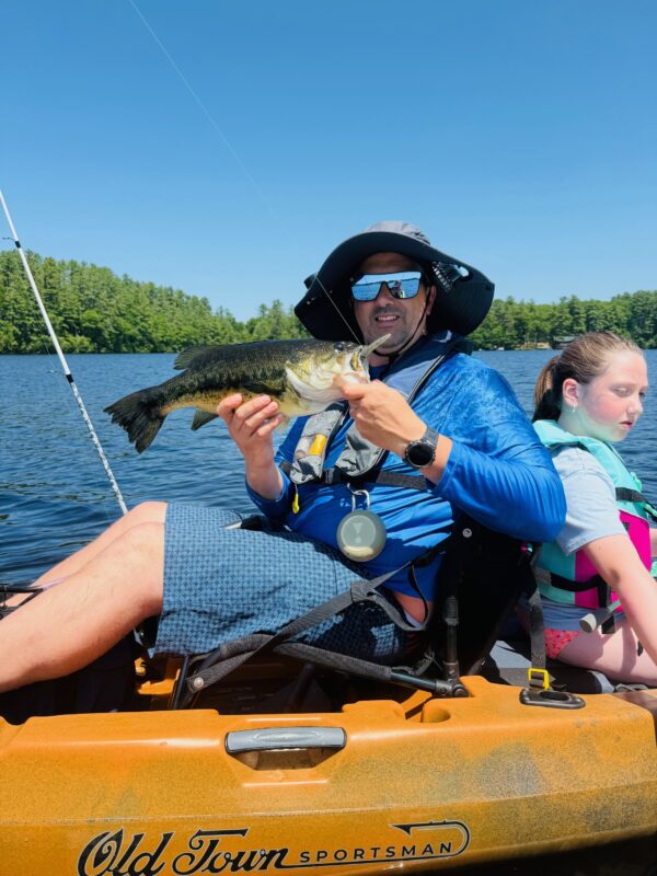 Kayak angler and his daughter with a largemouth bass